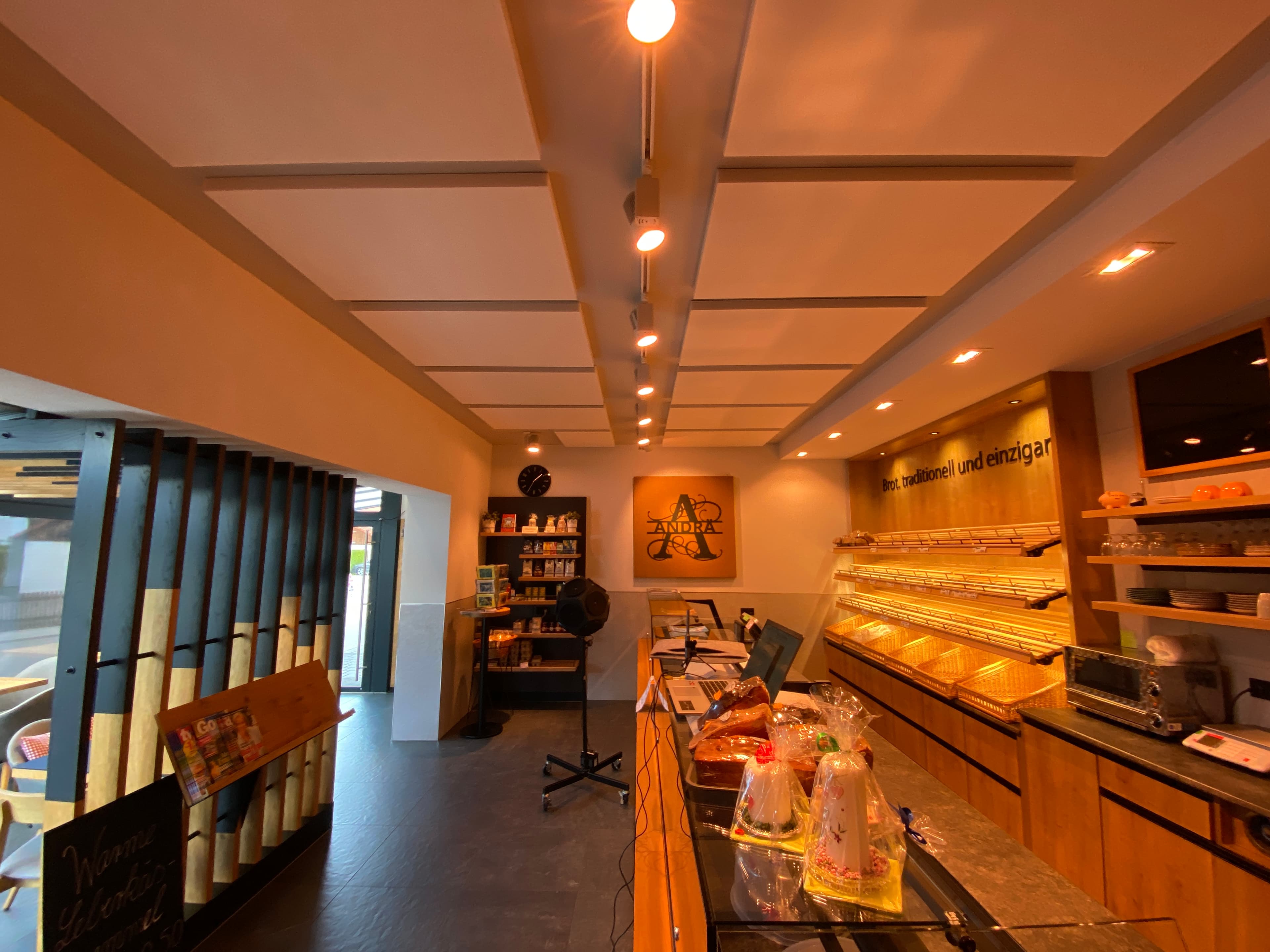 Bäckerei mit weißen, rechteckigen Schallschutzelementen an der Decke über der Verkaufstheke.